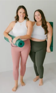 Two women who work at the CC Studio wearing yoga pants and athletic tops and holding yoga mats.