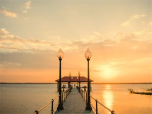 The Lake Jackson and City Pier Beach. The pier has light poles on either side and a railing. The photo was taken at sunset.
